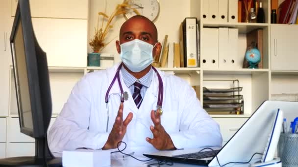 Latinskoamerická lékař nosí masku při psaní poznámek a čtení něco na notebook ve své kanceláři Stock Záběr