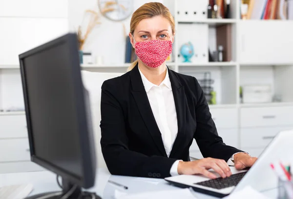 Kvinna i mask arbetar på kontoret — Stockfoto