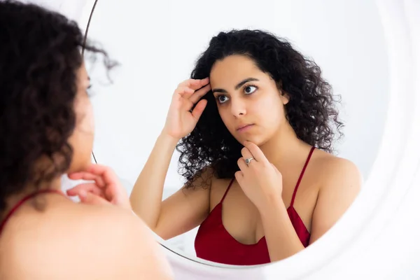 Mujer mirando su cara en el espejo por la mañana —  Fotos de Stock