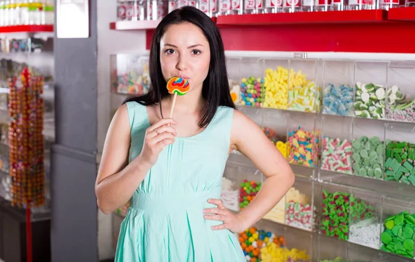 微笑的女孩在商店里吸棒棒糖 — 图库照片