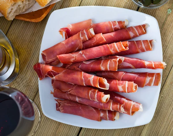 Традиционная испанская еда - рулоны иберийского хамона подаются на тарелке — стоковое фото