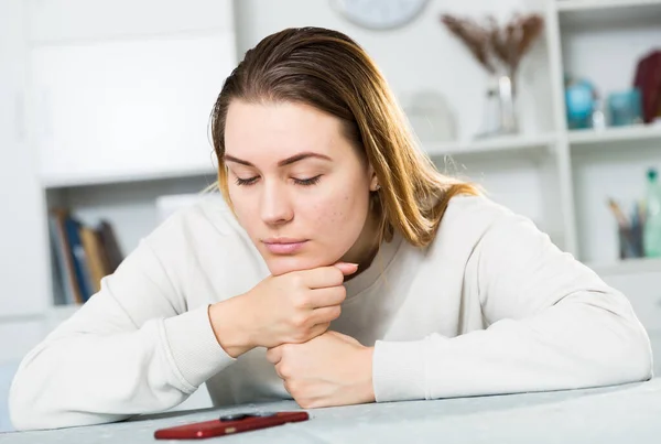 Ung kvinna är ledsen sitter med telefon eftersom hon är ensam — Stockfoto