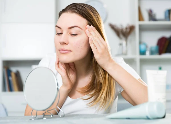 Smiling female is looking on her skin in the mirror — Stock Photo, Image