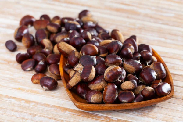 Raw edible chestnuts in wooden bowl on table — Stock Photo, Image