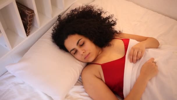 Menina morena atraente em pijama vermelho acordando na cama — Vídeo de Stock