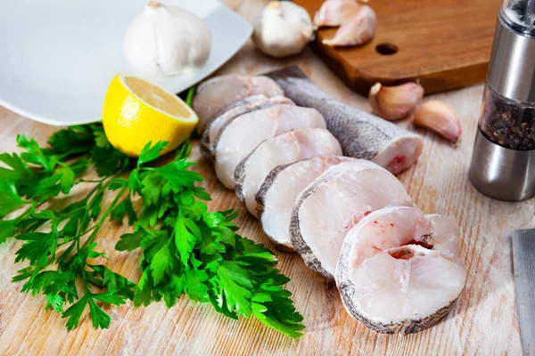 Fresh raw steaks of hake fish with greens and garlic, nobody — Stock Photo, Image