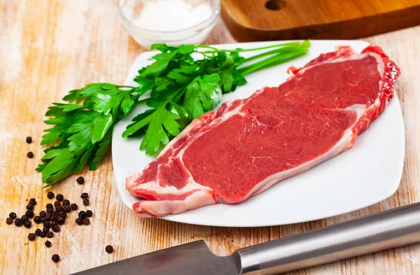 Close up of pieces of striploin served with parley on wooden table — Stock Photo, Image