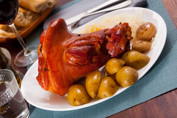 Appetizing pork knuckle and sauerkraut served with potatoes and onion — Stock Photo, Image