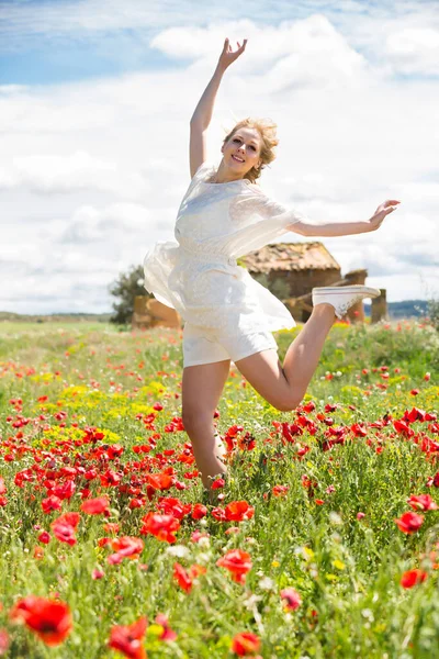 Fine young female jumping in poppy field — Stock Photo, Image