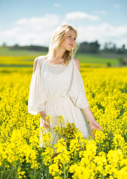 Junge Frau im gelben Rapsfeld posiert im weißen Kleid — Stockfoto