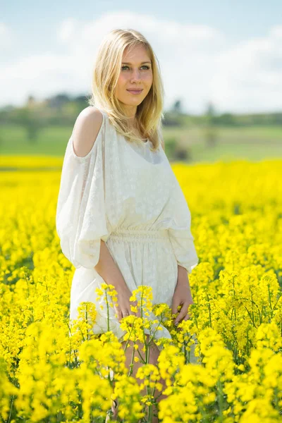 身着白衣的年轻女子在黄色油菜地摆姿势 — 图库照片