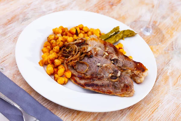 Traditionelles spanisches Hammelfleisch mit Bohnen auf blauem Teller auf Holztisch serviert — Stockfoto