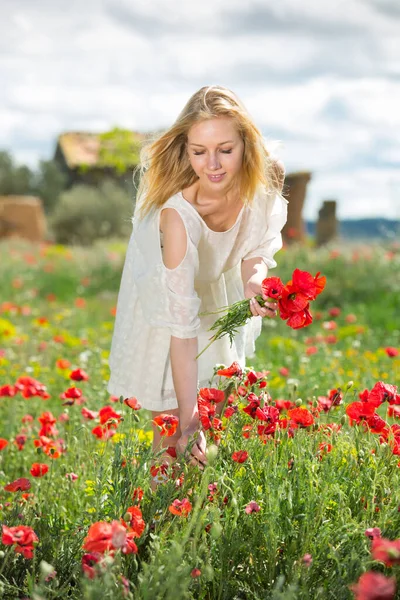 Gyönyörű fiatal nő fehér ruhában kezében csokor mák virágok — Stock Fotó