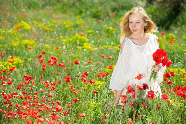 Vacker ung kvinna i vit klänning innehav bukett av vallmo blommor — Stockfoto