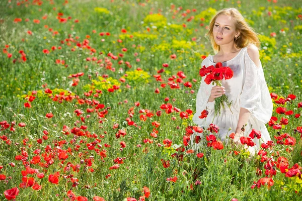 Frau in weißem Kleid hält Strauß Mohnblumen auf Feldern — Stockfoto