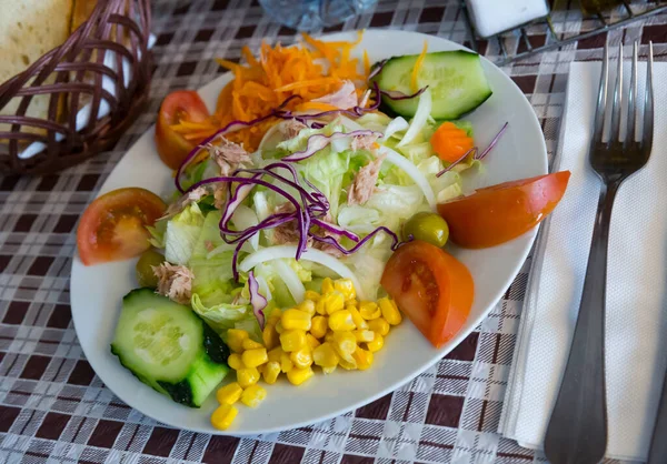 Sekoita salaatti vihanneksiin, keitettyyn porkkanaan, maissiin ja salaattiin lautasella — kuvapankkivalokuva