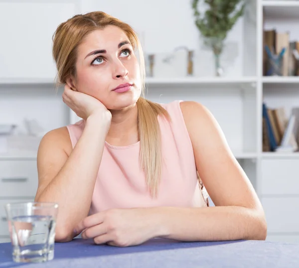 Droevige vrouw zit aan tafel alleen en overstuur — Stockfoto