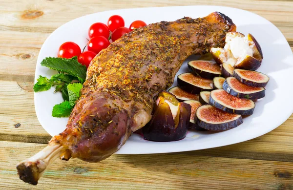 Baked shoulder of lamb served with fig, feta cheese, herbs and cherry tomatoes at plate — Stock Photo, Image