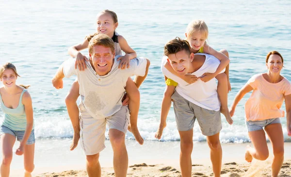 Padres con hijos caminan en la playa — Foto de Stock