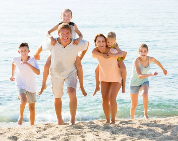 Föräldrar med barn går på stranden — Stockfoto