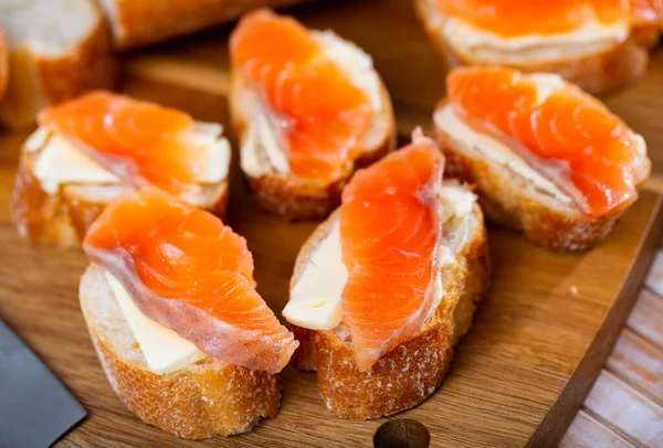 Sandwiches with butter and salted salmon on wooden board — Stock Photo, Image