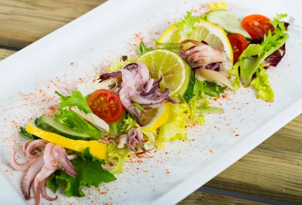 Ensalada de calamares cocidos con limón y ensalada de mezcla fresca en el plato — Foto de Stock