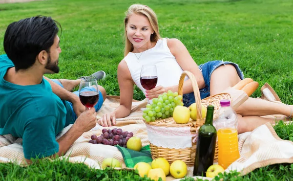 Pareja están hablando y bebiendo vino en tiempo de picnic al aire libre —  Fotos de Stock