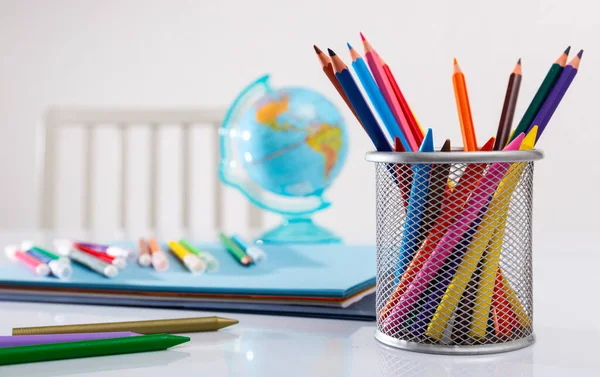 Iskolai kellékek az asztalon. Ceruza állványon, gömbben és jegyzetfüzetben — Stock Fotó