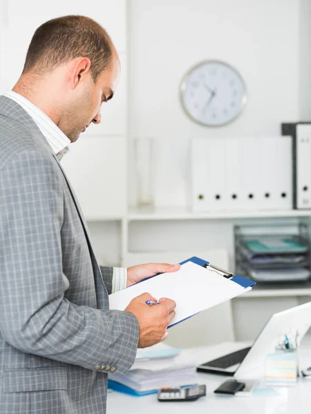 Uomo che lavora in ufficio al computer portatile con documenti — Foto Stock