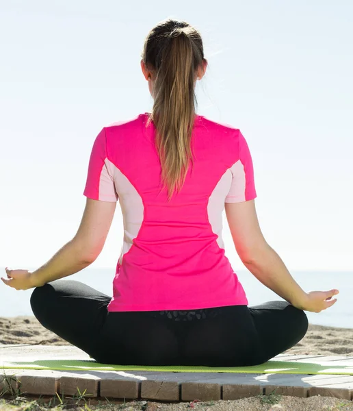 Flicka som utövar yoga poser på stranden — Stockfoto