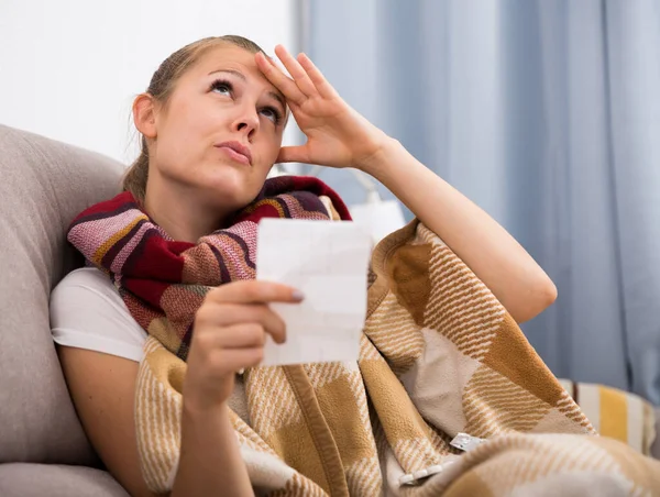 Sick woman lying with plaid and reading recipe — Stock Photo, Image