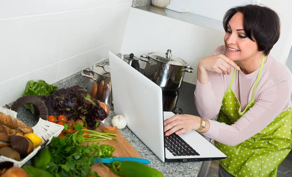 Woman with laptop in kitchen. — Stock Photo, Image