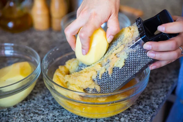 Rivning av potatis med hjälp av rivjärn för vegetabiliska pannkakor — Stockfoto