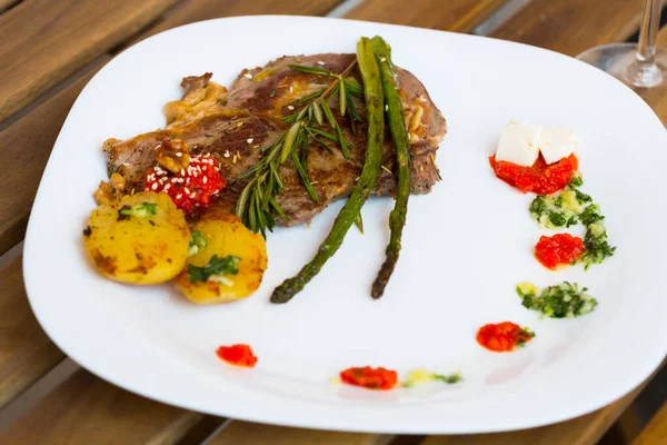 Gebratenes Kalbssteak mit gebackenem Gemüse, adjika auf Holzoberfläche — Stockfoto