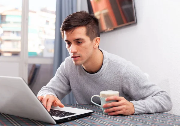 Uśmiechnięty mężczyzna pracuje z laptopem siedzącym przy stole — Zdjęcie stockowe