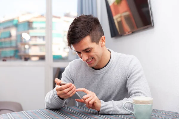 Jongeman belt bericht aan de telefoon in de woonkamer — Stockfoto