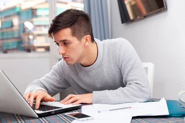 Trött man arbetar med bärbar dator i hemmet — Stockfoto