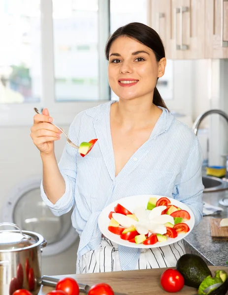 Frau probiert Gemüsesalat in Küche — Stockfoto