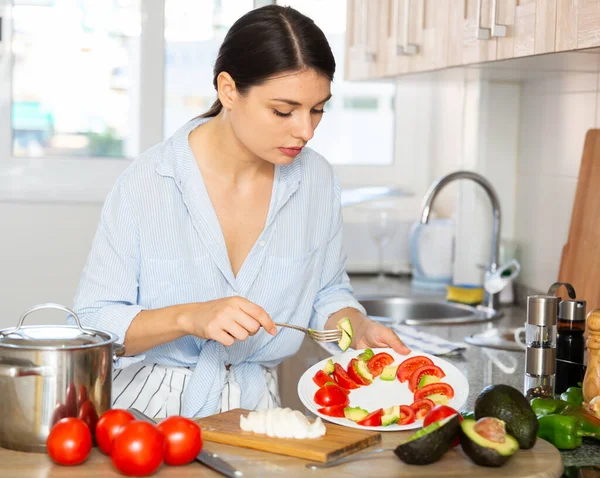 Huisvrouw bereidt tomaat en avocado salade in de keuken — Stockfoto