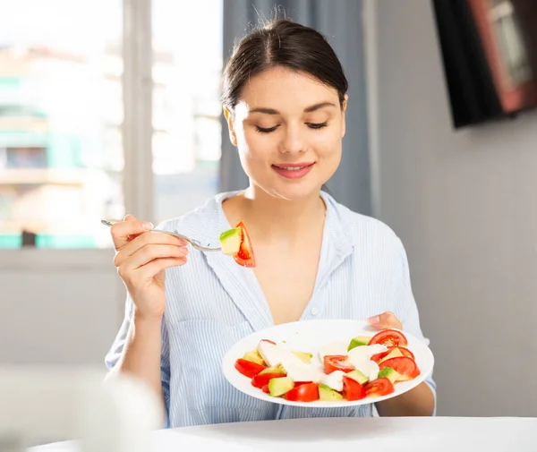 Женщина ест салат за столом — стоковое фото