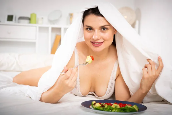Młoda sexy kobieta undeer koc jedzenie warzyw sałatka — Zdjęcie stockowe