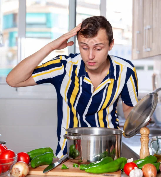 Zwykły człowiek nie umie gotować zupy w kuchni. — Zdjęcie stockowe