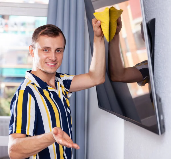 Householder wipes dust from the TV screen — Stock Photo, Image