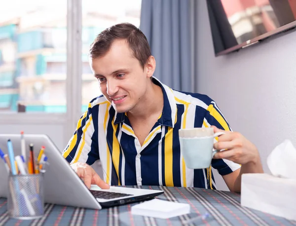 Человек работает за ноутбуком и пьет чай — стоковое фото