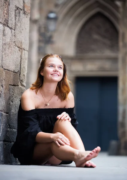 Jong vrouwtje zitten blootsvoets in de buurt van de stenen muur — Stockfoto