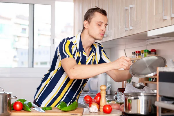 Мужской повар с кастрюлями и овощами на кухне — стоковое фото