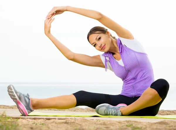 Kvinna som tränar yoga poser som sitter på stranden — Stockfoto