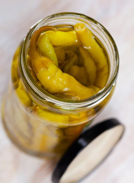 Pickled chilli peppers in a glass jar on wooden table — Stock Photo, Image