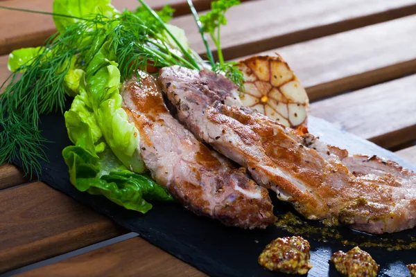 Tasty cooked fried pork with green leaves on plate at plate — Stock Photo, Image