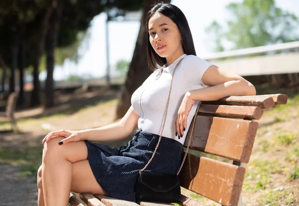 Привлекательная бразильская девушка сидит на скамейке в летнем парке — стоковое фото